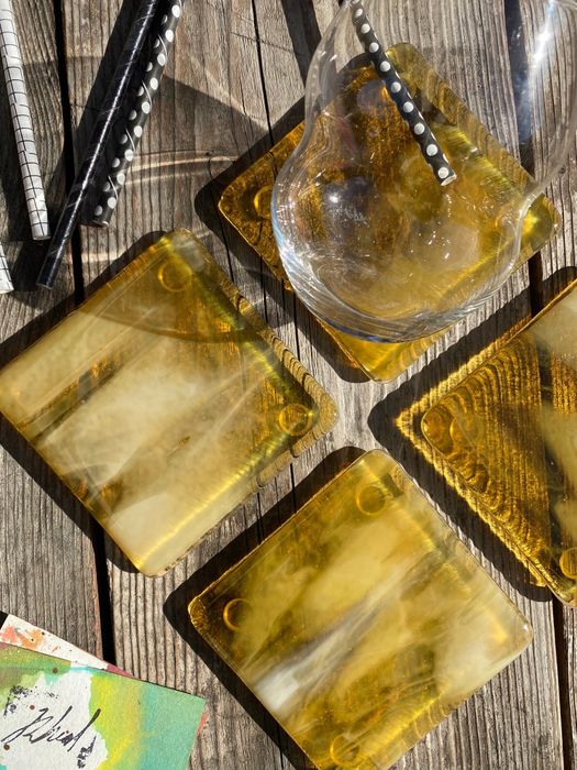 The marbled glass coasters in lemon ice color resting on a table.