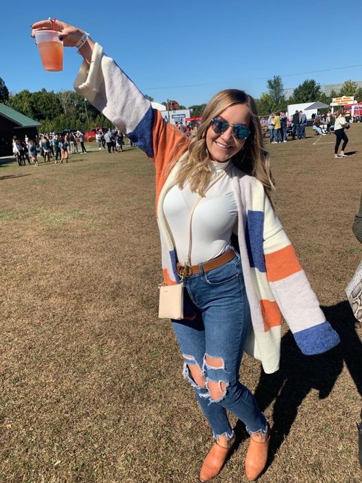 a reviewer rocking the cardigan in a vibrant mix of white, orange, and blue stripes