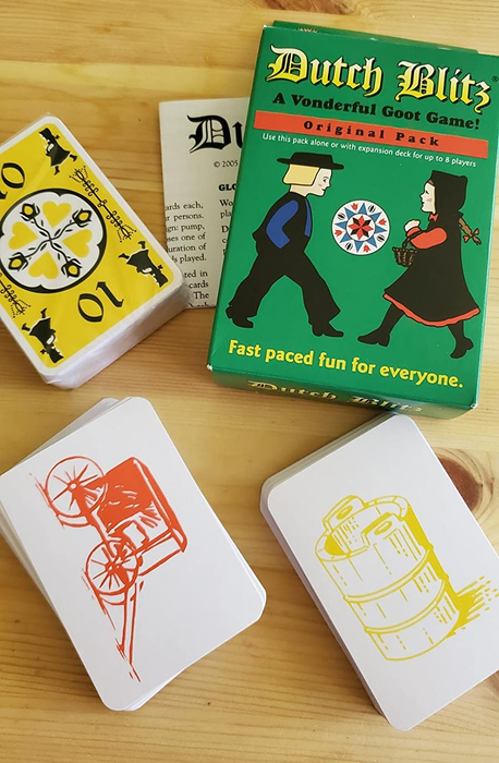 a reviewer's image featuring the card game box and two piles of cards, one displaying a yellow bucket design and the other an orange carriage motif 