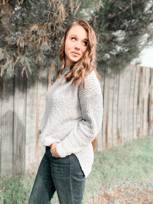 A reviewer wearing the sweater in light gray
