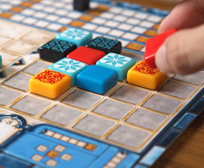 a person placing printed tiles onto a game board