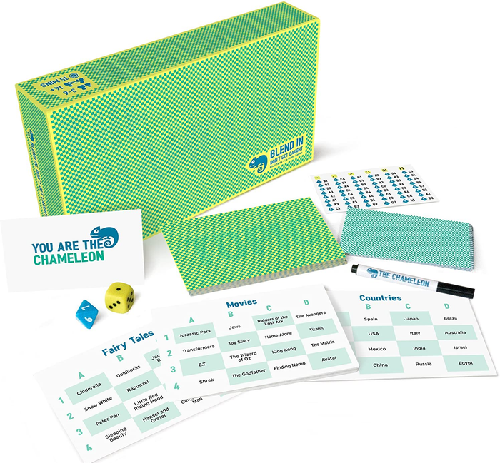 A game box for The Chameleon surrounded by playing cards, dice, and dry-erase cards for keeping score.