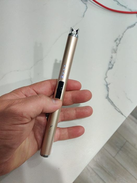 a reviewer holding a gold rechargeable lighter