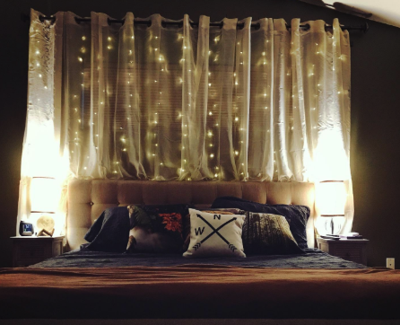A reviewer's photo of twinkle lights draped behind their bed.