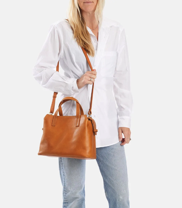 A model carrying a tan leather handbag.