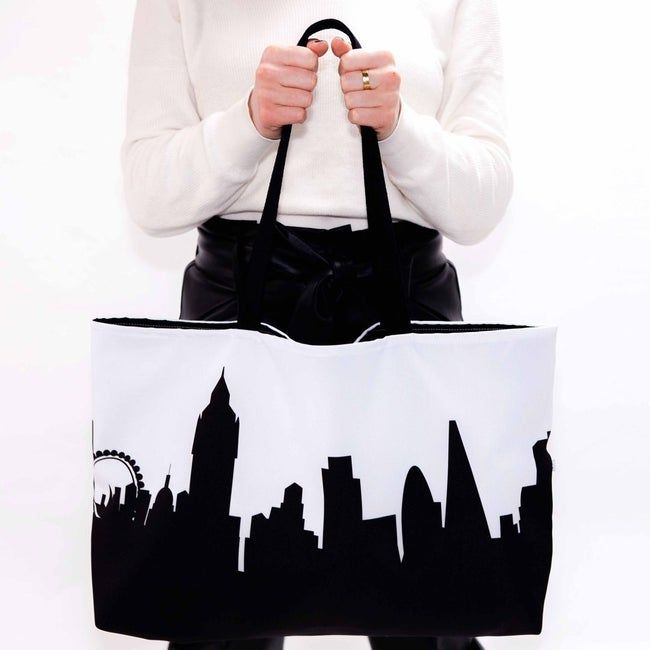A model holding a tote bag with the London skyline design