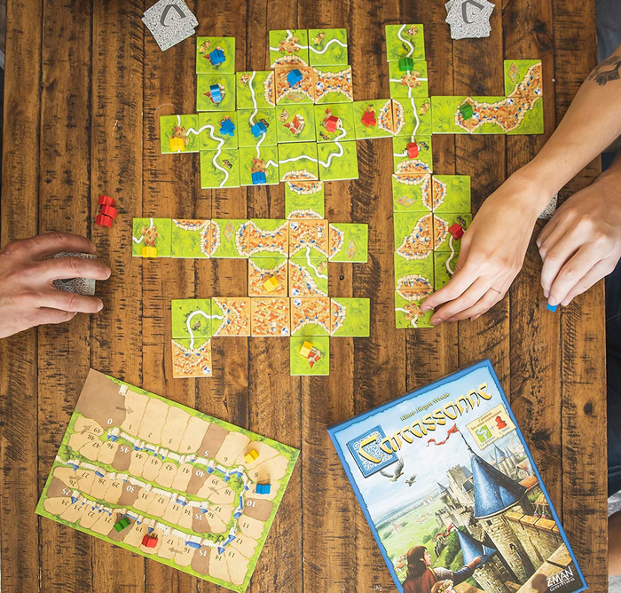 an aerial view of a table arranged with Carcassonne tiles and the game box placed nearby 