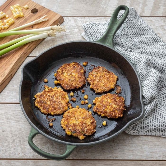 A green pan with fried potato pancakes sizzling in it.