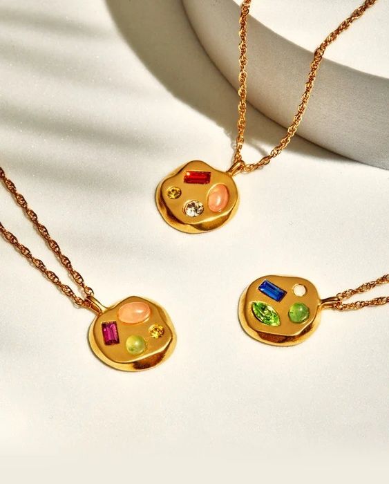 Three gold pendants, each featuring a different gemstone, adding a unique touch to each piece.