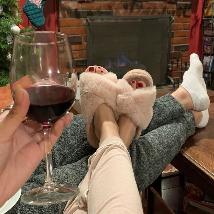 A reviewer enjoys the comfort of the pink slippers with their feet casually propped up.