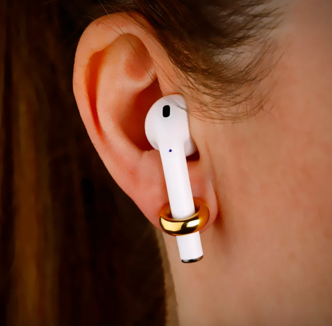 A person wearing a gold earring, with an AirPod securely held in their ear