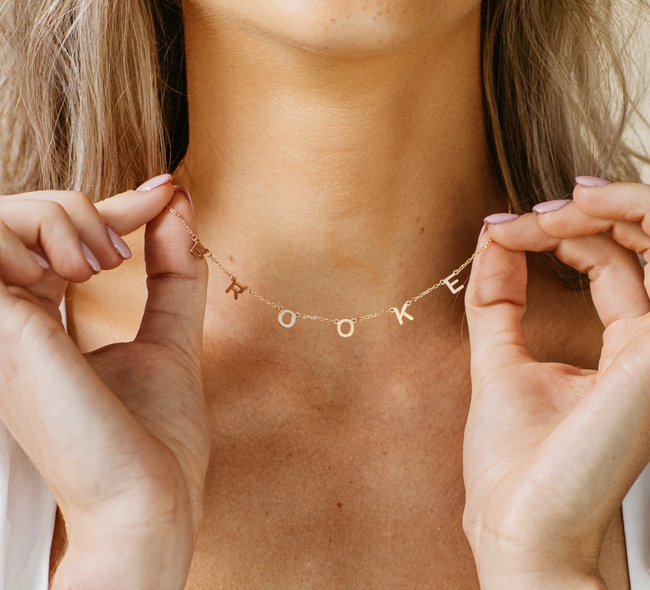A model wearing a name necklace with the name 'Brooke' displayed