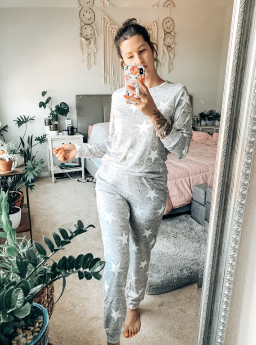 A reviewer dressed in a grey long sleeve and pants set adorned with white stars.