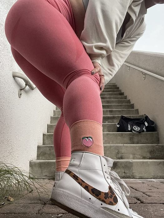 A reviewer sports sneakers with peach-colored socks peeking from the top, each adorned with an embroidered peach.
