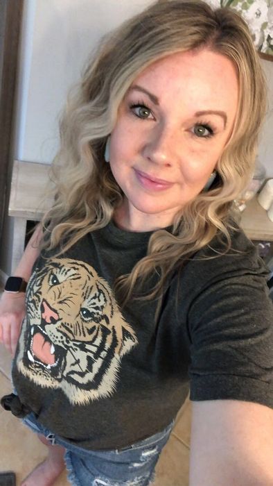A reviewer wearing the dark gray tank featuring a tiger graphic