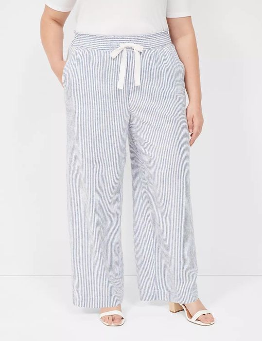 A model sporting striped drawstring pants and white sandals, posing against a minimalist backdrop.
