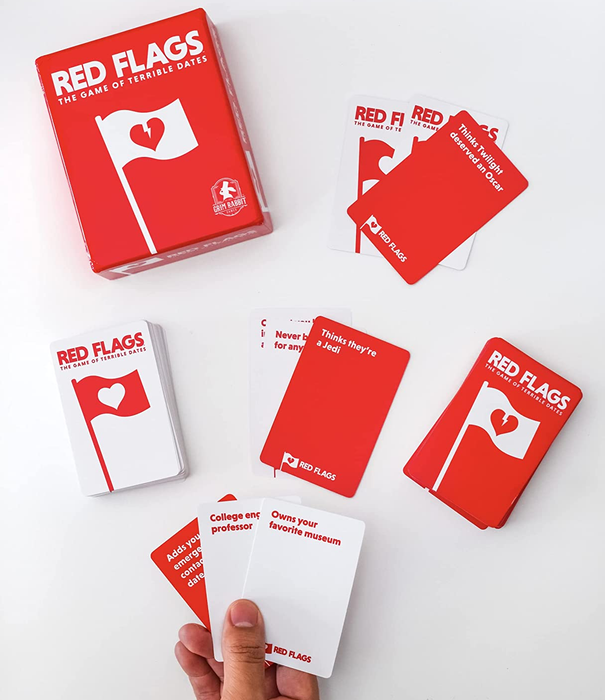 a person holding a hand of cards, two decks, and the game box 