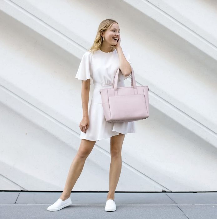 A model showcases the pink tote bag elegantly draped over her arm.