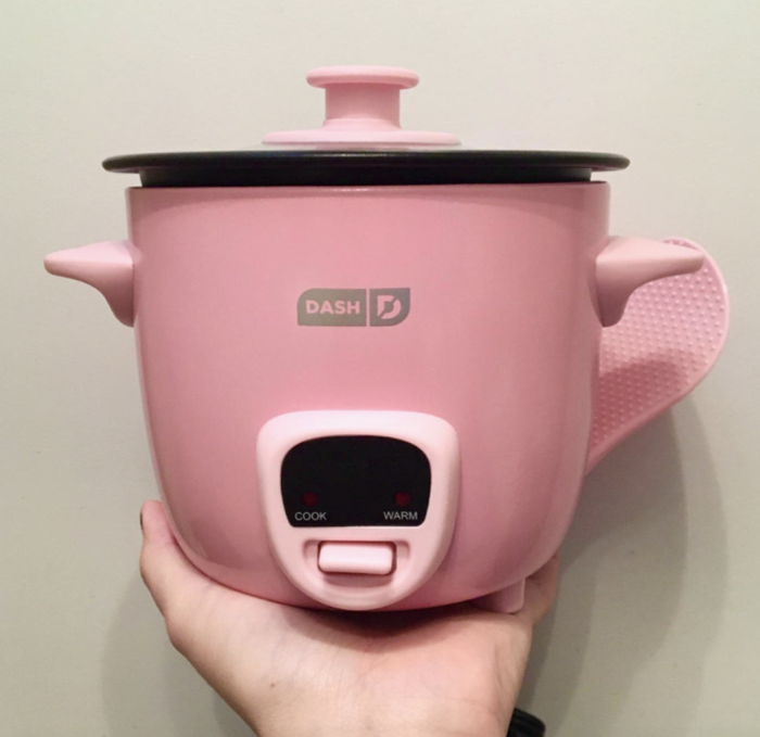 A reviewer holding the mini pink rice cooker.
