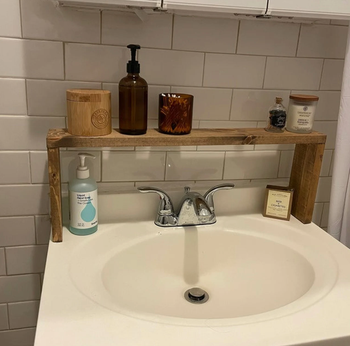 The shelf above a sink displaying lotion, candles, and other decorative items
