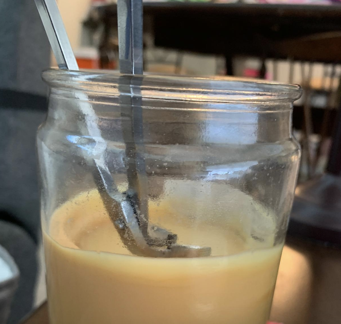 A reviewer demonstrating the use of a silver candle wick trimmer.