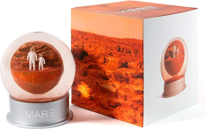 A Mars-themed snow globe featuring astronauts, displayed alongside its packaging adorned with an image of Mars, perfect for space-inspired home decor