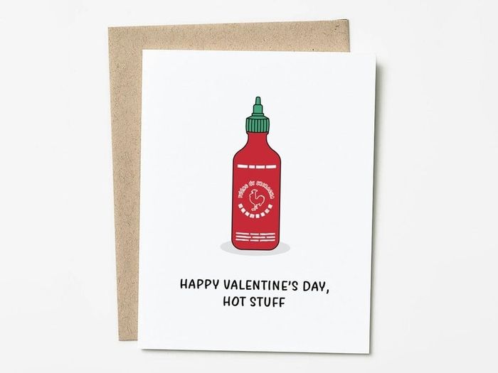 A card featuring the text "happy valentine's day, hot stuff" alongside an illustration of a sriracha bottle