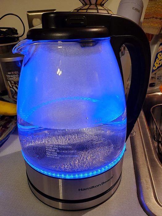 Reviewer's photo of an electric kettle glowing with a blue light while in use