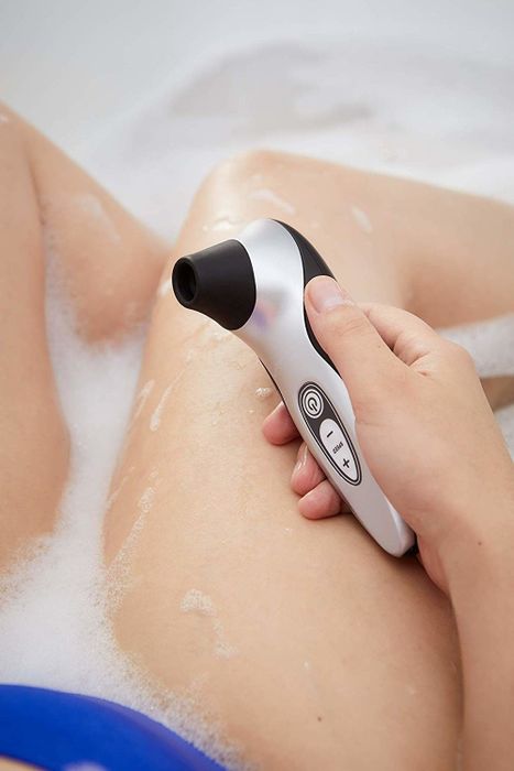 An individual in a bathtub holding a sex toy.