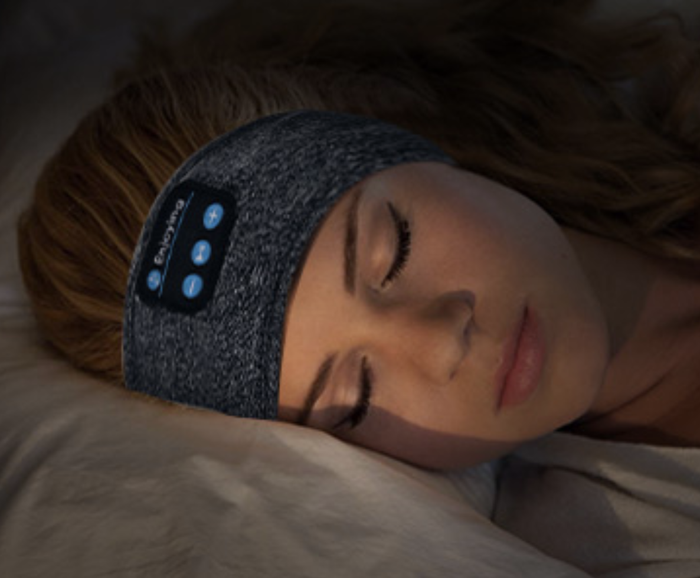 A person peacefully sleeping with a headband-style sleep headphone around their ears.