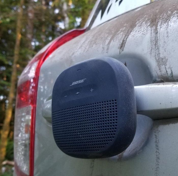 A reviewer’s photo of the black Bose speaker mounted on the back of a car in a wooded area