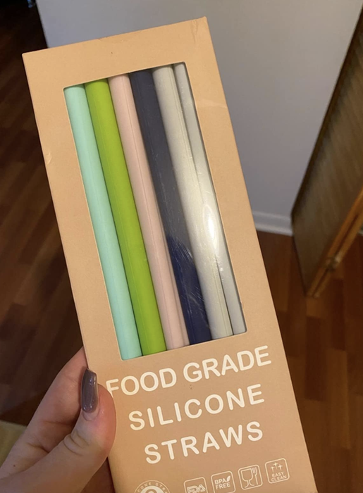 A reviewer holding a pack of colorful silicone straws.