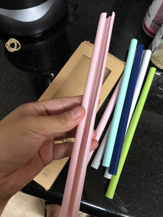 A reviewer demonstrating how to open a pink silicone straw for cleaning.