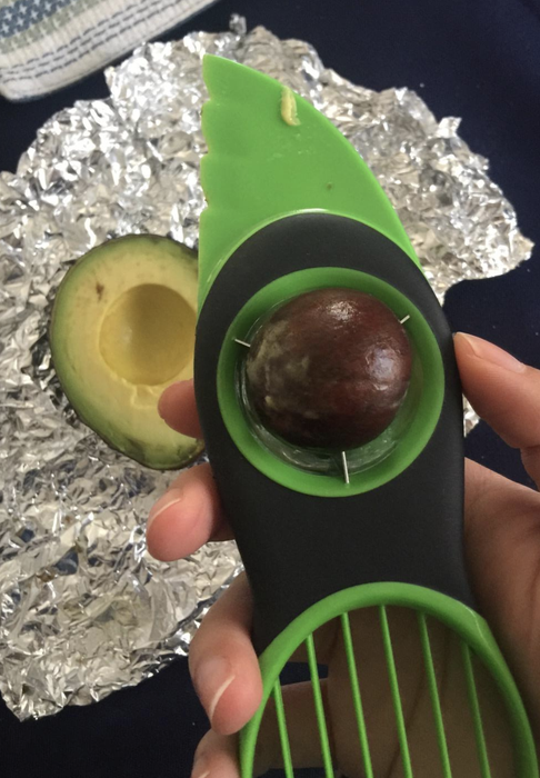 A reviewer showing a photo of the green and black OXO avocado slicer tool.