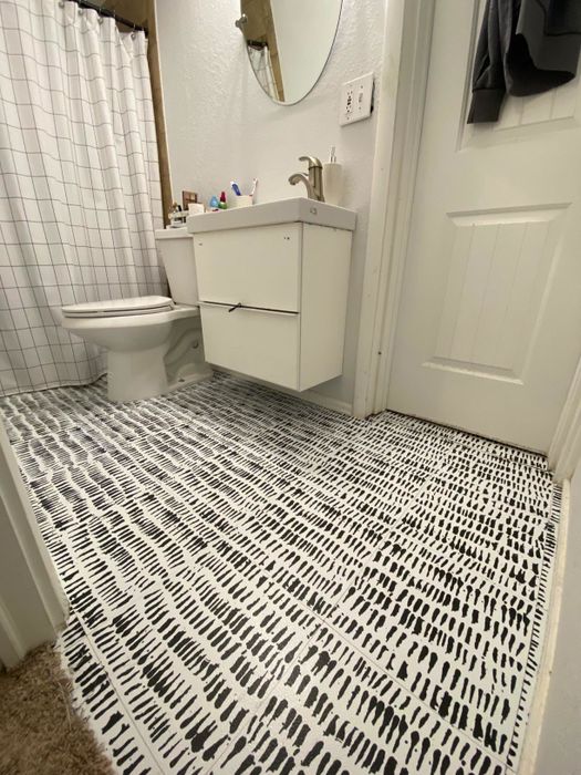 An after photo displaying white tiles with artistic black smudges covering the floor