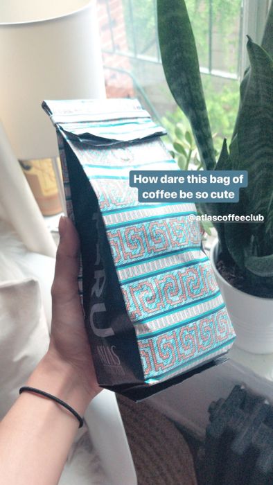 A hand holding a bag of freshly roasted coffee beans.