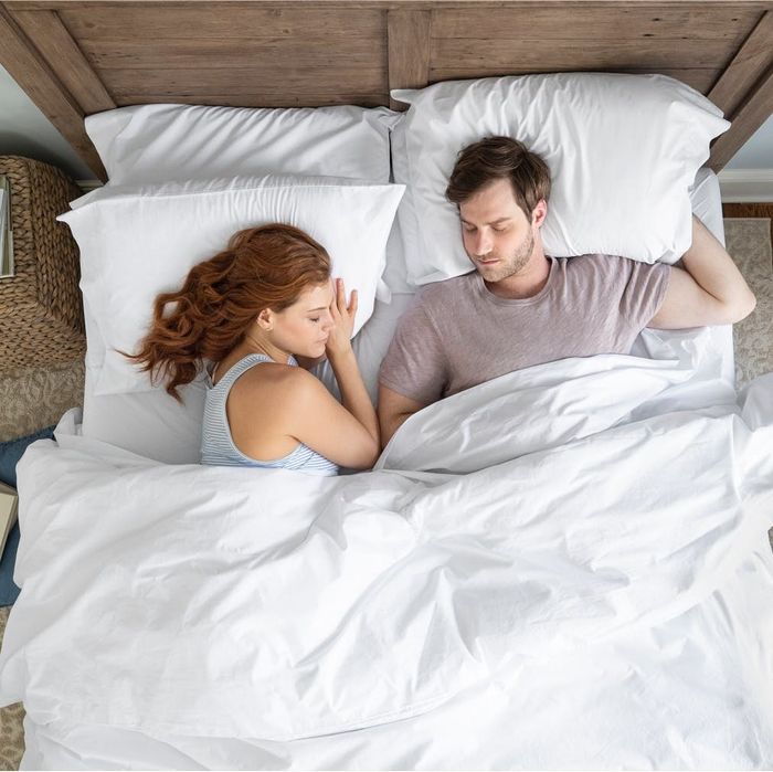 Two people relaxing under a plush white duvet.