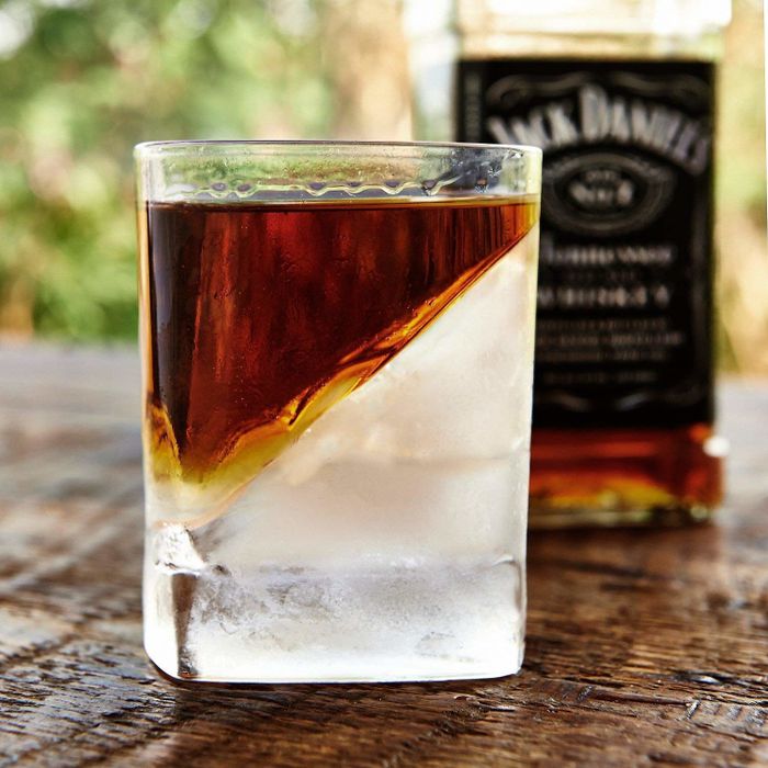 A glass filled with whiskey and ice inside.
