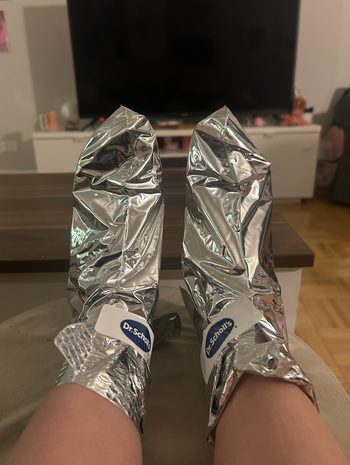 Feet elevated, wearing two metallic foot masks
