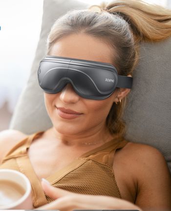 A person unwinding with a RENPHO eye massager, wearing a sleeveless top and holding a cup, demonstrating the benefits of this self-care product