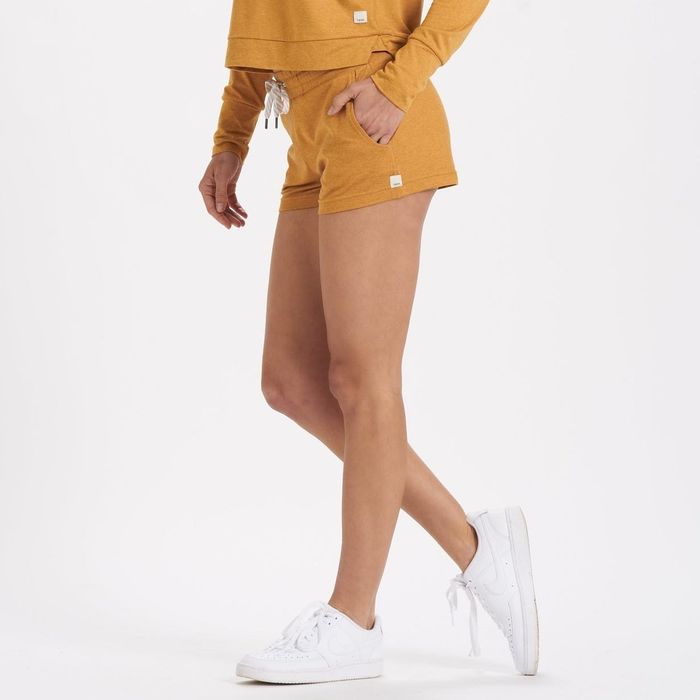 Model flaunting orange, thigh-length halo performance shorts in action.