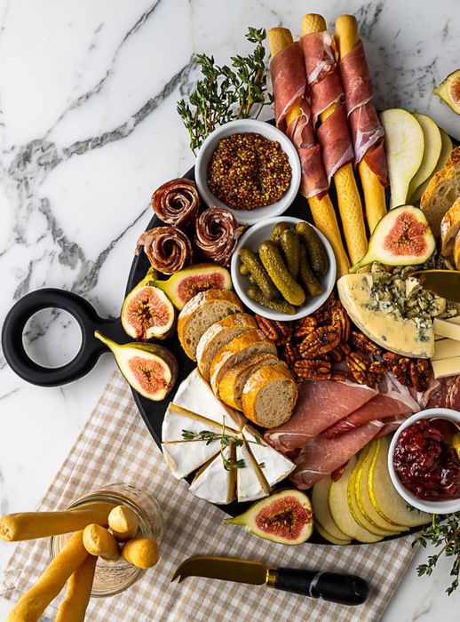 An artfully arranged charcuterie board featuring an assortment of meats, cheeses, figs, pickles, bread, and spreads, designed for an upscale dining atmosphere.