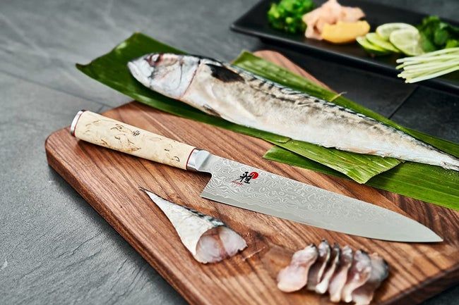 The Miyabi knife resting on a cutting board beside some fresh fish, ready for action.