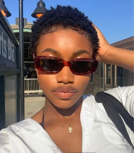 a model wearing the hair oil, showcasing her short curls