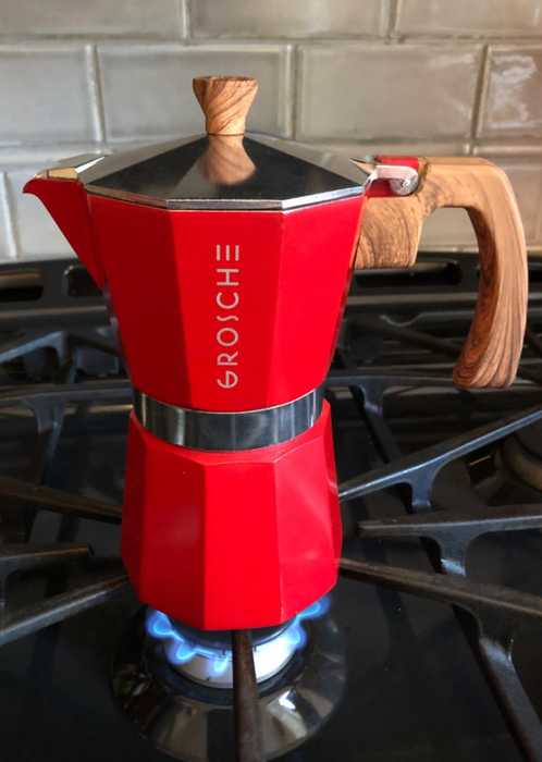 A red moka pot heating up on the stove, ready to brew a delicious cup of espresso.