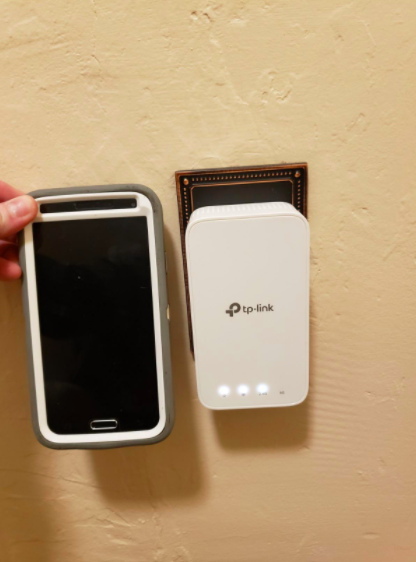 The extender placed alongside a phone for scale, showing that they are approximately the same size.