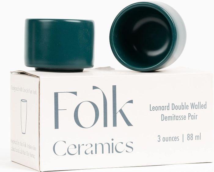 Two teal demitasse cups resting on a Folk Ceramics box labeled