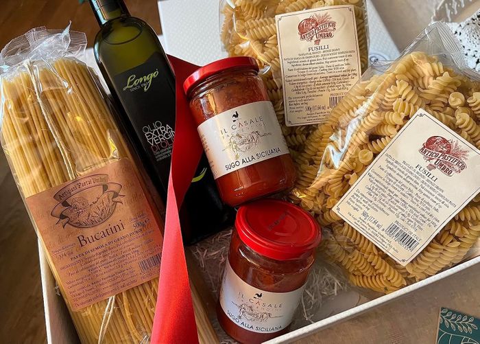A handpicked assortment of authentic Italian pasta and sauces, featuring bucatini, fusilli, and Sicilian sauce, accompanied by a bottle of extra virgin olive oil.