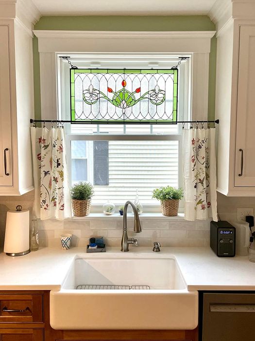 A stained glass panel elegantly hanging above a kitchen sink.
