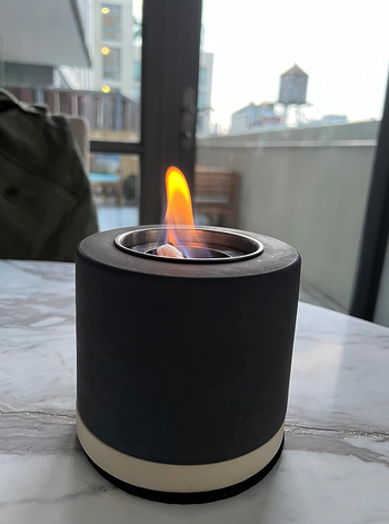 A compact tabletop fireplace with a visible flame